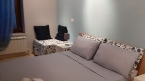 Een slaapkamer met een bed, nachtkastje, lamp en stoel.