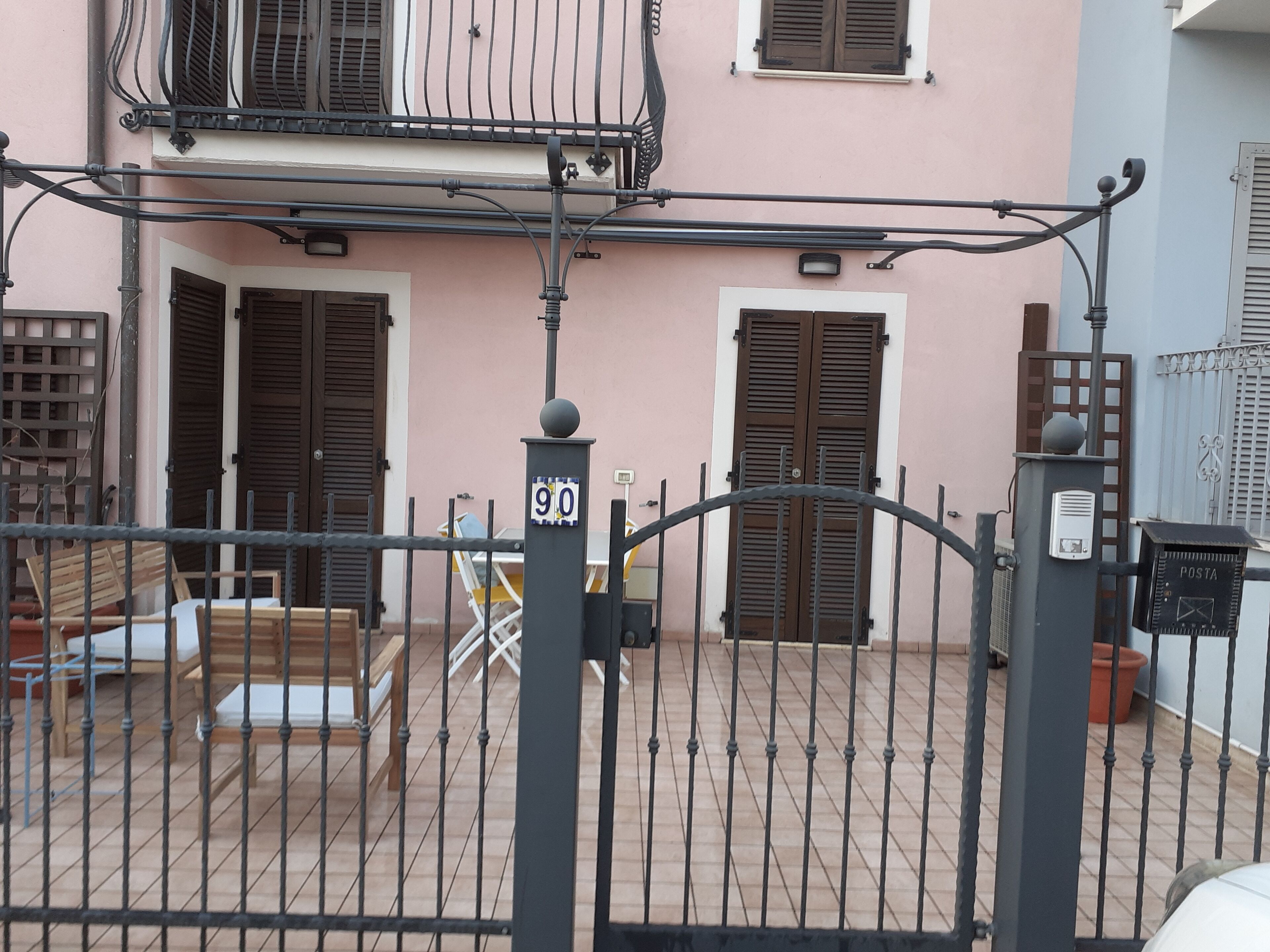 A gated courtyard with a metal fence, a bench, and a table.