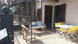 Een buitenpatio met een tafel, stoelen, een bank en een decoratieve bol.