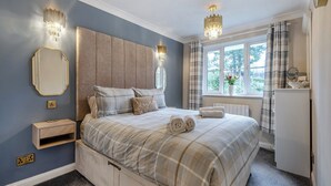 A bedroom with a bed, bedside table, mirror, and a window with curtains.