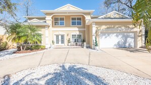 A two-story house with a garage, a driveway, and a well-maintained lawn. - 7BD 6BA, Pool&Spa, Walk to Beach, PutPut, Dream Backyard, 10 min. to Downtown!  (St. Augustine)