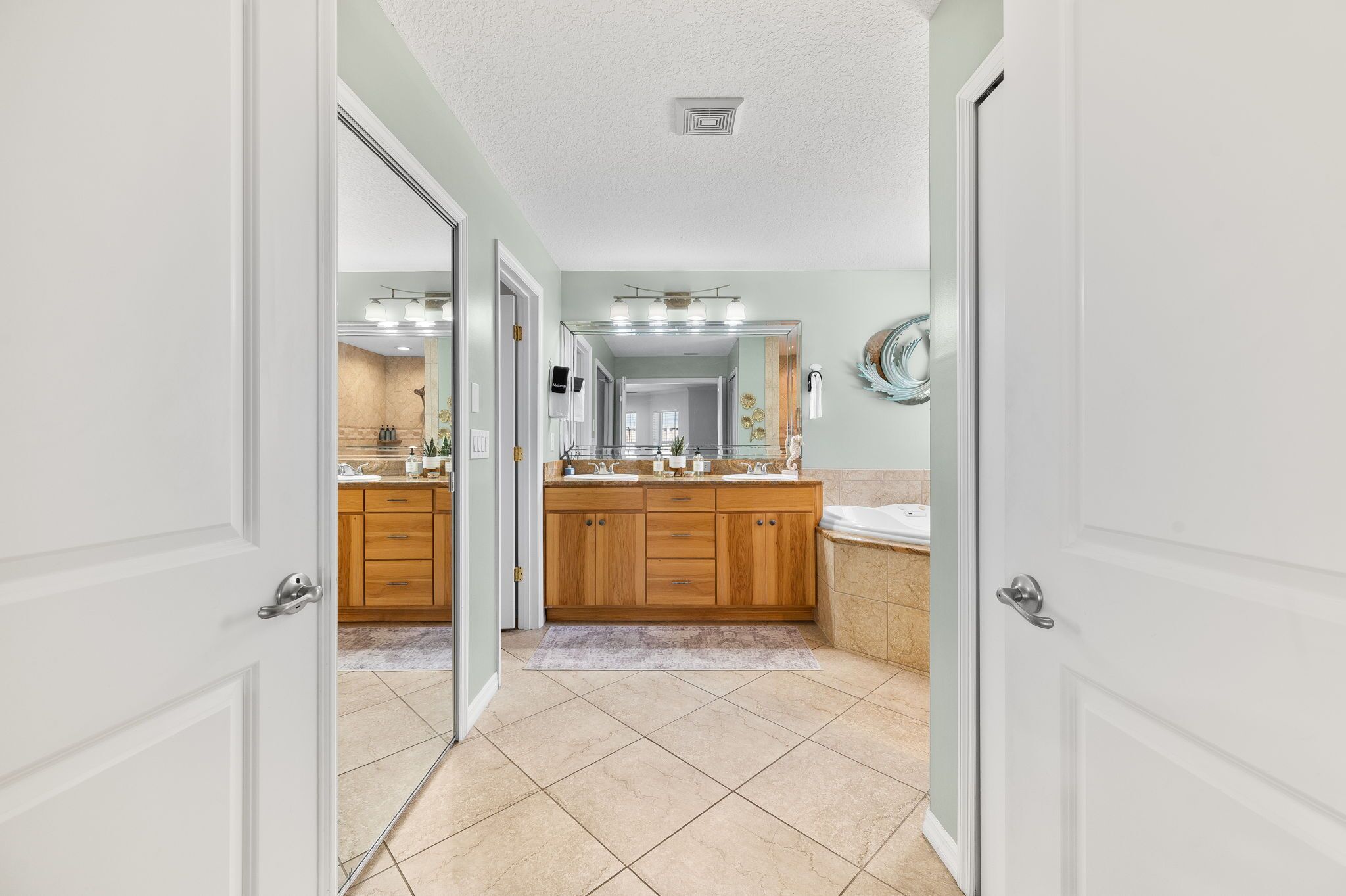 A bathroom with a large mirror, wooden cabinets, and a sink.
