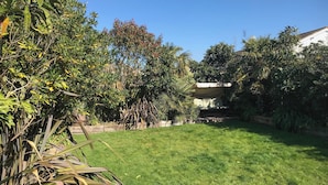 Une pelouse bien entretenue, parsemée d’arbres et d’arbustes de différentes espèces.