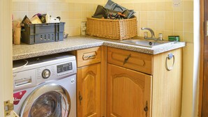 Un espace buanderie comprenant un lave-linge, un panier en osier et un évier.