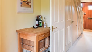 Un couloir avec une armoire en bois, un tableau encadré et une porte dotée d’un chambranle blanc.