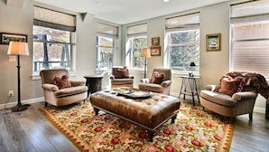Un salon avec un grand tapis à motifs floraux, deux fauteuils, un canapé et une table basse.