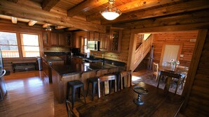 Een houten chalet van binnen met een keuken, eethoek en een trap.
