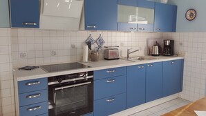 Eine Küche mit blauen Schränken, einem Siemens-Ofen, einem Toaster, einer Kaffeemaschine und einem Spülbecken.