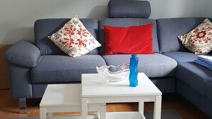 Ein Wohnzimmer mit grauem Sofa, weißem Couchtisch und blauer Vase.