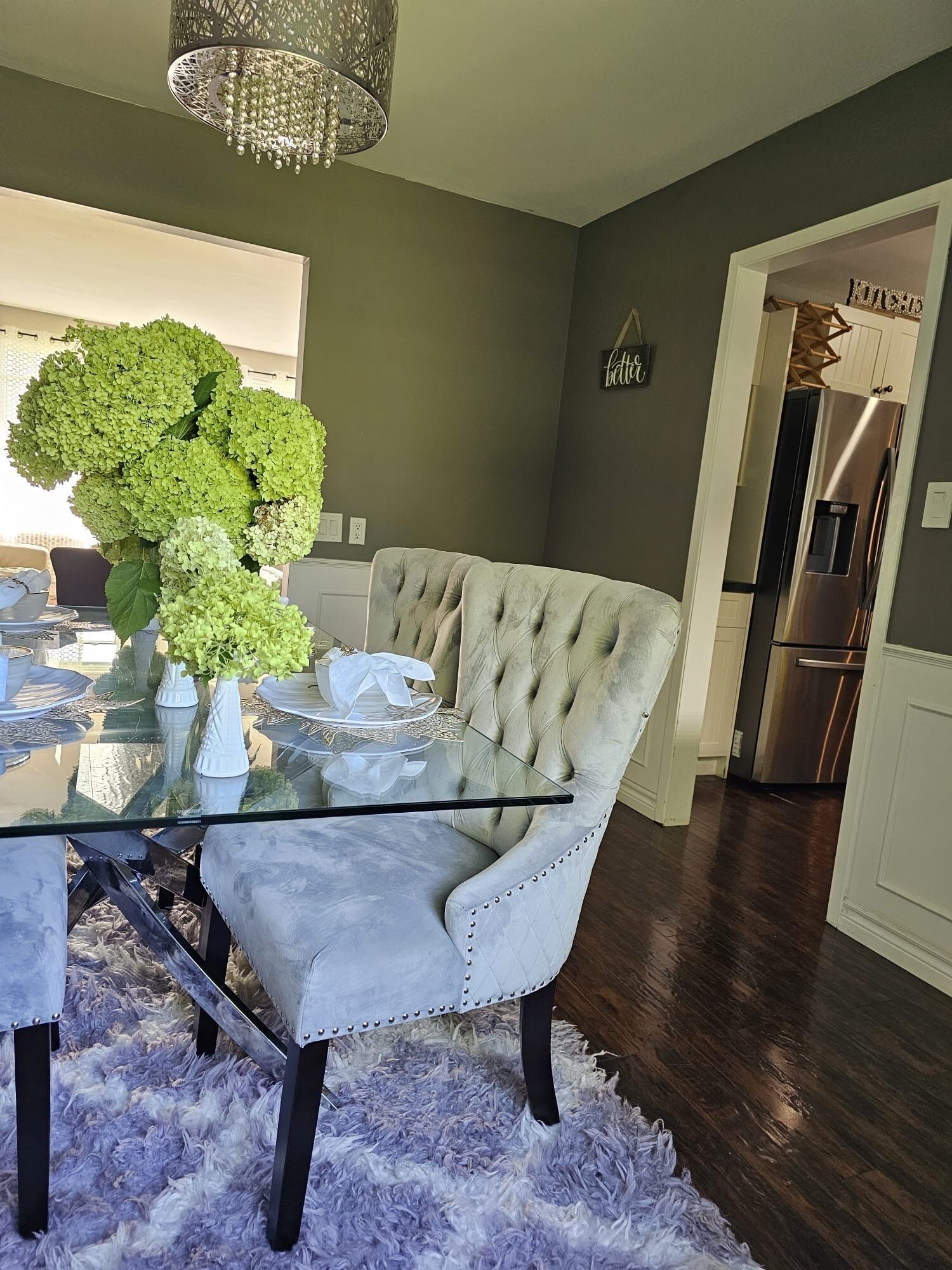 A dining area with a glass table, a tufted armchair, and a fluffy rug.
