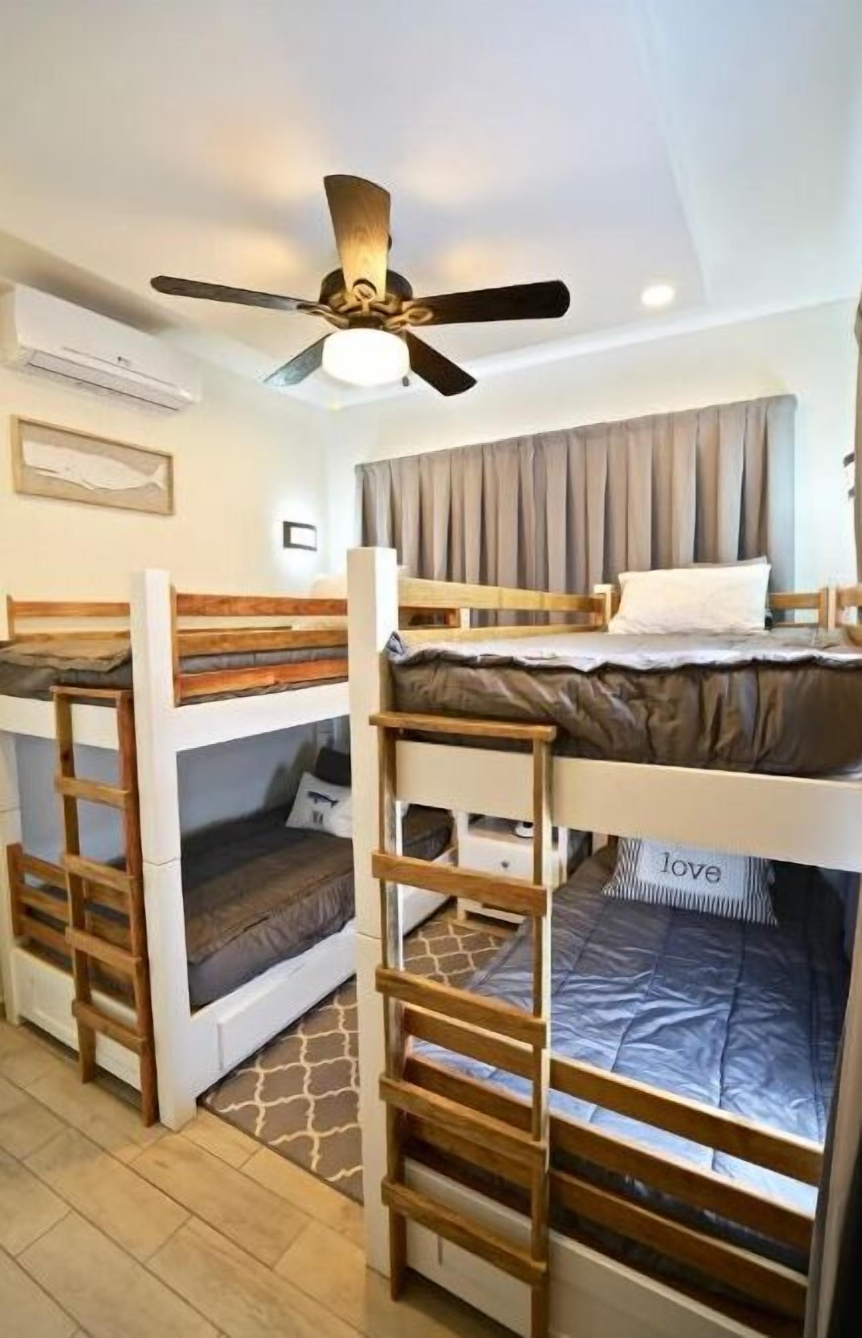 A room with bunk beds, a ceiling fan, and a framed picture on the wall.