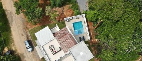 Vista aérea de uma casa com piscina, um pátio e uma garagem.