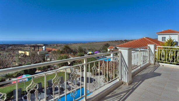 A balcony with a pool, outdoor seating, and a view of the sea.