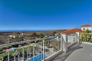 Un balcone con piscina, area relax esterna e vista sul mare.