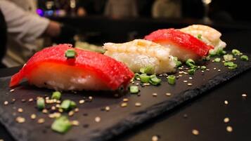 A sushi dish with a dark slate plate, garnished with green onions and sesame seeds.