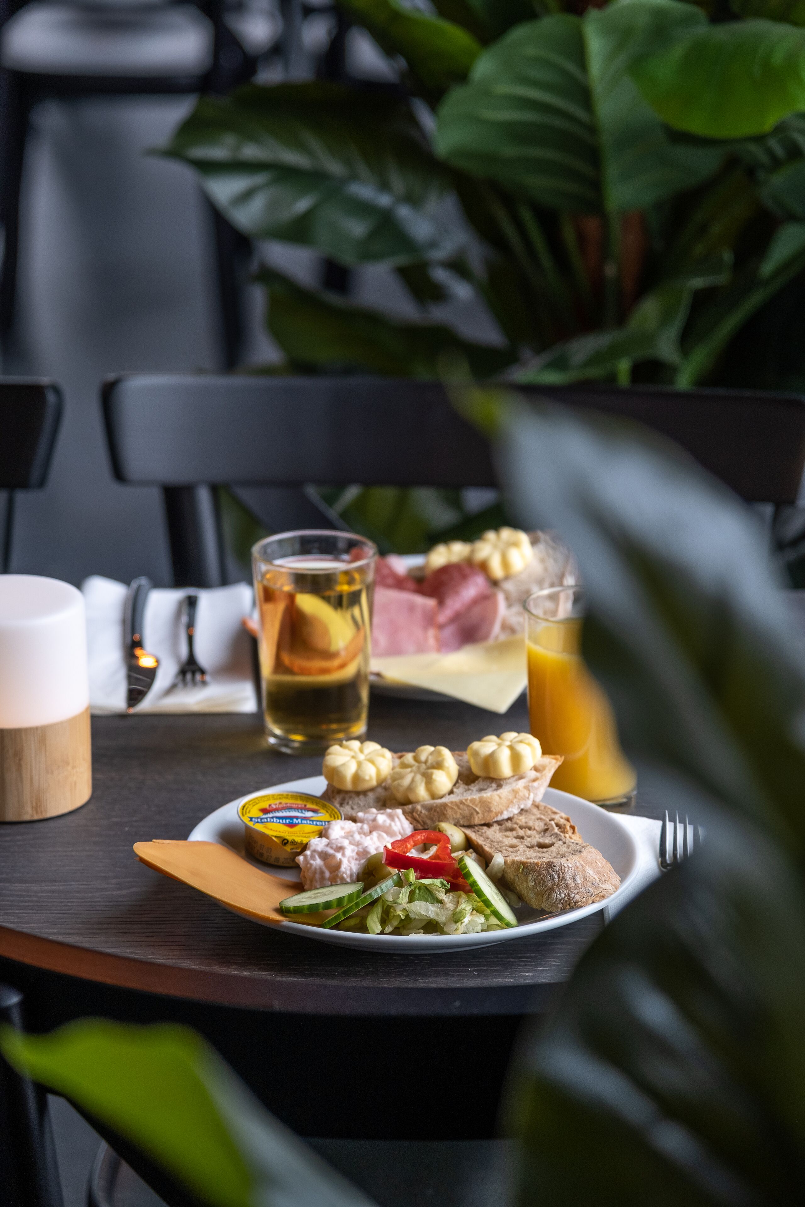 A table with a plate of food, a glass of juice, and a cup.