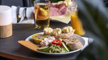 A table with a plate of food, a glass of juice, and a cup.