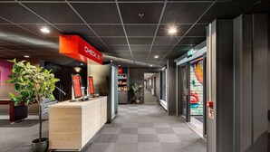 A hotel reception area with a check-in counter, a potted plant, and a colorful mural on the wall. - Aiden By Best Western Trondheim Airport (Stjordal)