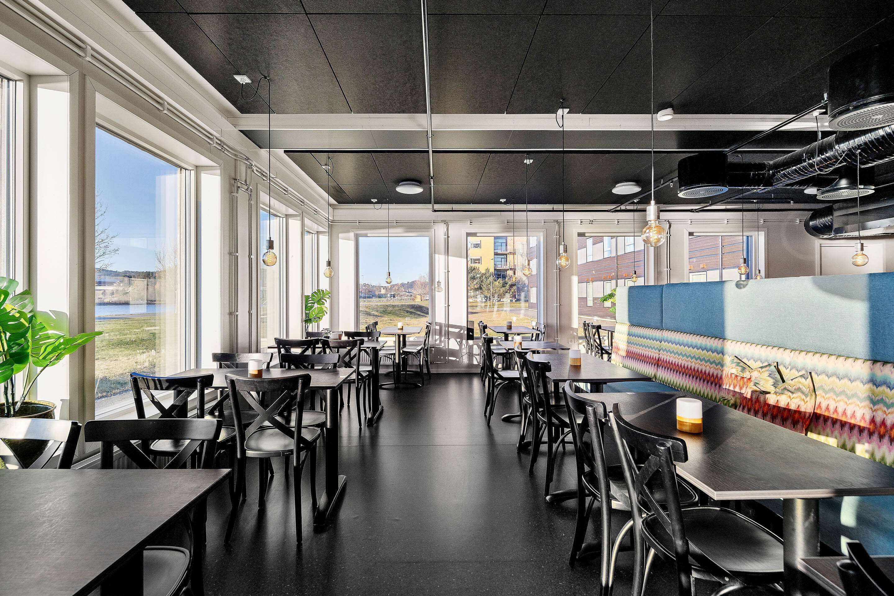 Un comedor espacioso con techos altos, ventanas amplias y luminarias modernas.
