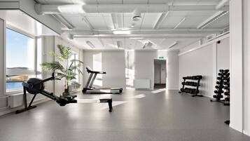 Un gimnasio con equipo de ejercicios, cinta de correr y vistas al exterior.
