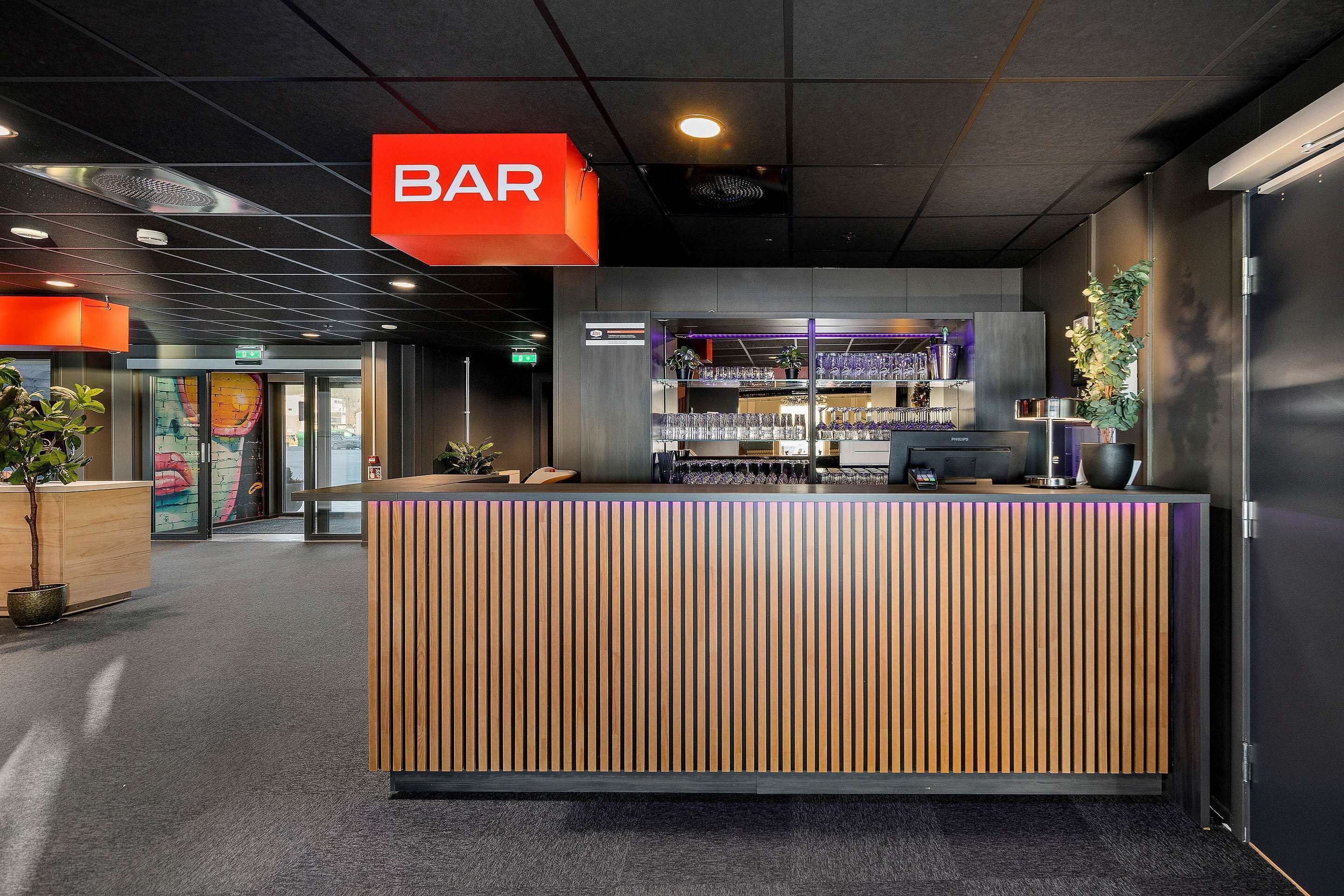 Una zona de recepción con un mostrador de madera, una barra y un letrero que indica un bar.