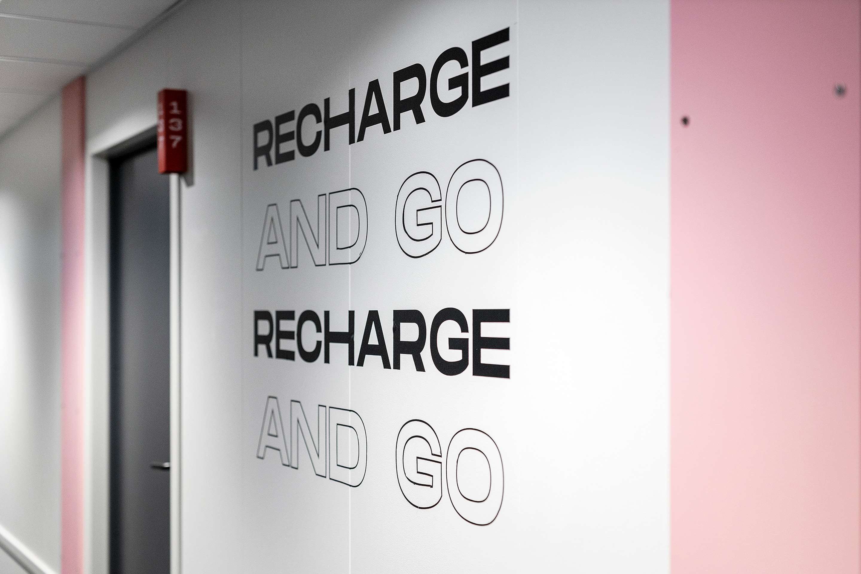 Un mur sur lequel est inscrit en grandes lettres, dans une police de caractères sans empattement, le texte répété : « RECHARGEZ ET PARTEZ ».