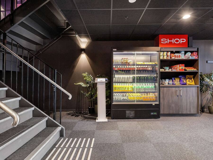 A modern indoor setting with a staircase, a vending machine, and a 'SHOP' sign.