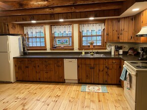 Una cocina con armarios de madera, un lavamanos de acero inoxidable y un lavavajillas.