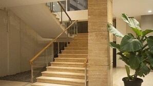 Eine moderne Treppe mit Glasgeländern, einer Stein Säule und einem Blumentopf.