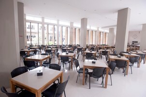 Un comedor amplio con varias mesas y sillas, ventanas grandes y un diseño moderno y limpio.