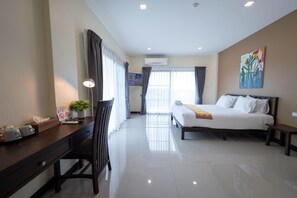 A hotel room with a bed, a desk, a chair, a TV, and a painting on the wall.