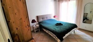 Quarto com cama, mesa de cabeceira, abajur e espelho na parede.
