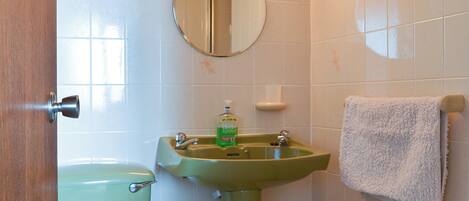 Un baño con inodoro, lavabo y un perchero para toallas.