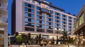 Un hotel de varios pisos con un diseño moderno, que destaca un letrero prominente de "HYATT CENTRIC", ventanas amplias y un área de entrada bien iluminada.