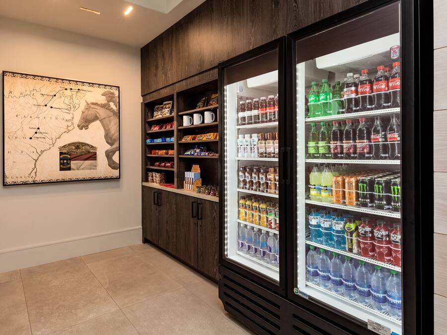 A room with a large refrigerator stocked with various beverages, a wooden cabinet with snacks, and a map on the wall.