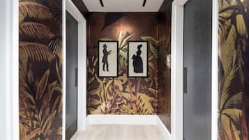 A hallway with a tropical mural, framed pictures, and wooden flooring.
