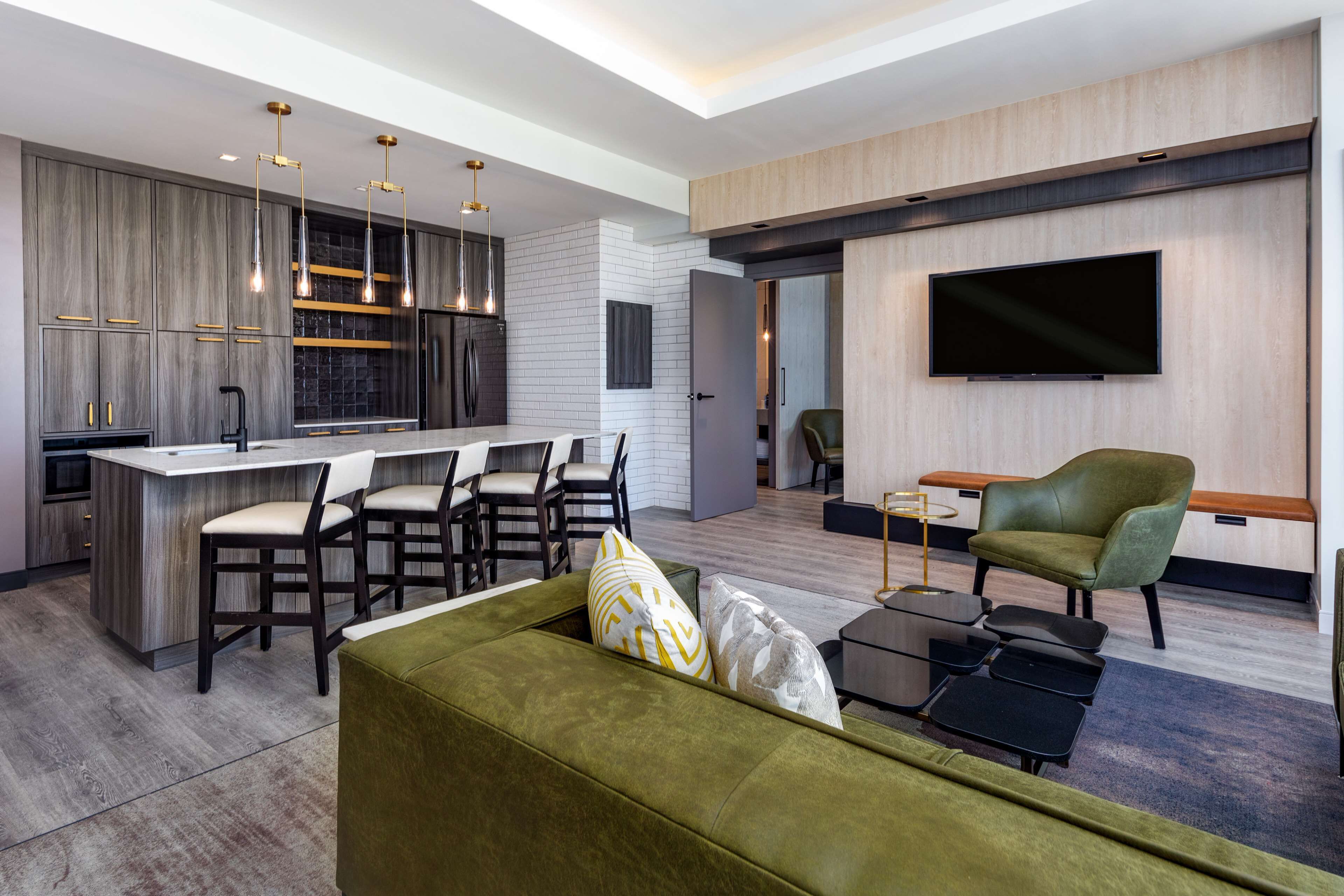 Une cuisine moderne dotée d’un îlot central, de tabourets de bar et de luminaires suspendus.