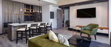Una cocina moderna con una isla central, taburetes de bar e iluminación colgante.