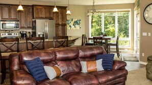 A spacious living room with a leather sofa, dining area with a table and chairs, and a kitchen with wooden cabinets and stainless steel appliances.