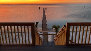 Un pontile di legno con vista su un molo che si protende verso l'acqua al tramonto.