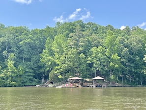 Vista su un lago con un pontile, un gazebo e una collina boscosa.