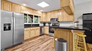 Una cocina moderna con armarios de madera, electrodomésticos de acero inoxidable y una zona de bar.