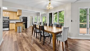 Una cocina amplia con armarios de madera, una mesa de comedor con sillas y ventanas grandes.