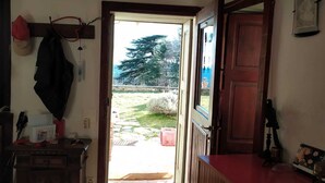 Ein Zimmer mit einer Holztür, die nach draußen führt, einem kleinen Tisch mit Gegenständen darauf und einem roten Schrank.