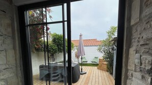 A room with a sliding glass door leading to an outdoor patio with a wooden deck, outdoor furniture, and a garden area.