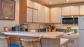 A kitchen with wooden cabinets, a microwave, a toaster, and a sink.