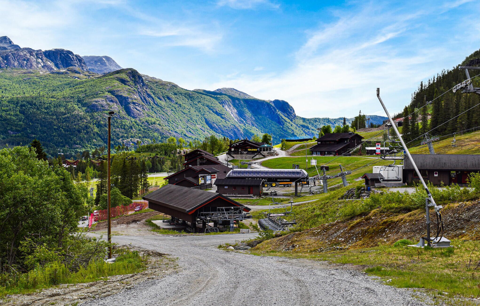 A mountain village with traditional wooden buildings, a ski lift, and a clear view of the surrounding mountains.