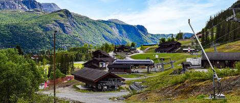 A mountain village with traditional wooden buildings, a ski lift, and a clear view of the surrounding mountains.
