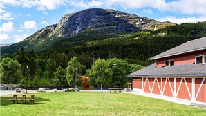 A red building with a sloped roof, a picnic table, and a mountainous backdrop. - Stunning apartment in Hemsedal (Hemsedal)