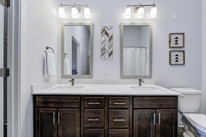 A bathroom with two sinks, dark wooden cabinets, and a mirror with lights above. - *LUXURY WALK IN THE PARK-2* (Fishers)